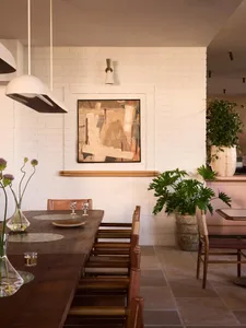 Modern dining room with wooden tables, concrete floor, brick wall, and leather chairs.