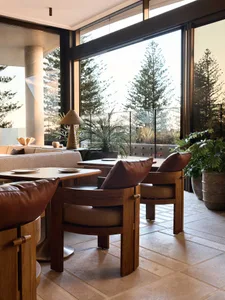 Modern lounge area with wooden furniture, concrete walls, and leather cushions in a restaurant setting.