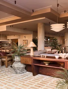 A spacious Mediterranean restaurant with wood furnishings, concrete accents, and cement flooring.