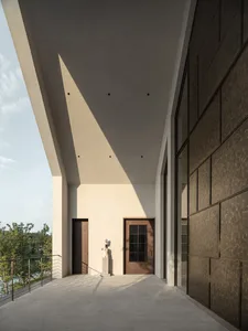A minimalist exterior with concrete walls and a sloped roof, featuring a statue and a wooden door.