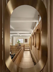 A modern interior corridor with wood panels and a curved path leading to a seating area.