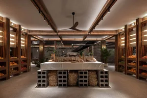 Industrial-style restaurant interior with wooden structures, concrete elements, and hay accents.