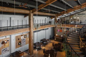 Large, spacious, industrial-style commercial space featuring wooden beams, brickwork, and glass elements.