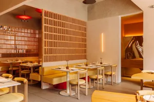 Modern minimalist restaurant interior with sleek, yellow furniture, and contemporary design features.