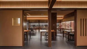 Modern restaurant interior with wooden tables, rustic wooden walls, and warm lighting.