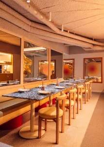 A modern restaurant interior with marble tables, wooden chairs, and glass windows.