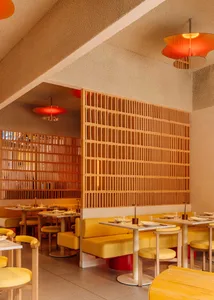 Modern restaurant interior with yellow seating, wooden accents, and red pendant lights