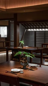 餐廳室內照片，展示木質餐桌椅，中央擺放盆栽盆景，帶有傳統日式元素