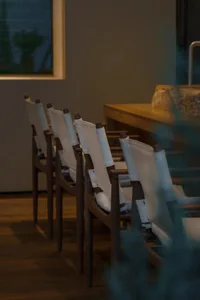 A row of wooden chairs with white fabric seats arranged in a modern interior space.