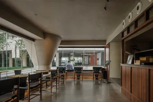 A contemporary lobby with concrete walls and floors, featuring minimalist design elements and a warm, inviting atmosphere.