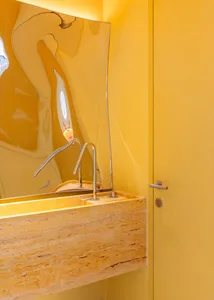 Modern marble bathroom with a yellow wall and a unique, abstract mirror.