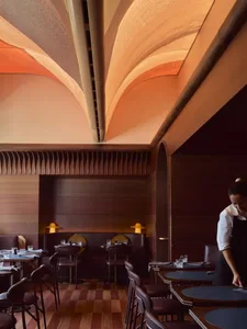 Modern restaurant interior with plush seating, metallic accents, and acoustic panels.
