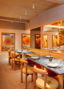 Modern restaurant interior with marble tables, leather seating, and wood accents.