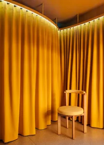 A minimalist interior with yellow curtains and a wood chair.