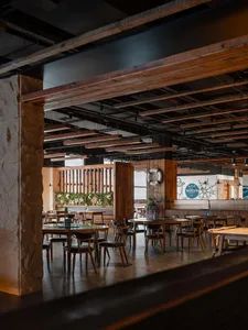 工業風格的餐廳室內，配有木製餐桌、餐椅與石材柱子