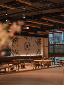 Interior design of a modern restaurant featuring wooden furniture and wall murals with marine-themed illustrations.