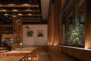 現代工業風餐廳室內，搭配木質家具與裸露木樑。