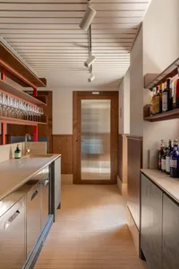 Modern kitchen with wooden walls, metallic cabinets, and glass door.