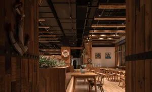Interior of a restaurant with industrial design elements made of wood, including wooden tables, chairs, and ceiling beams.