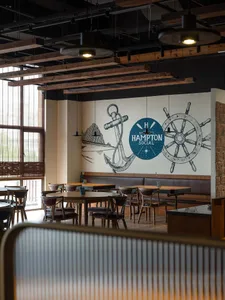 Industrial-themed restaurant interior with wooden tables, chairs, and beams