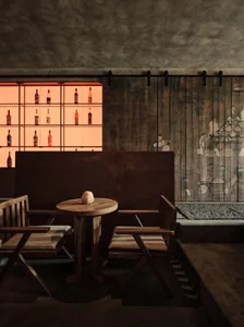 Industrial-style bar with wooden furniture and shelves displaying bottles.