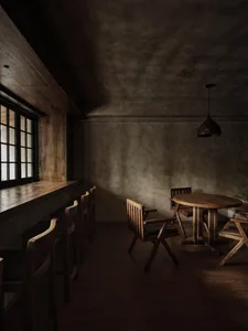 Industrial-themed restaurant interior with wooden furniture and concrete walls.