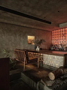 A modern bar interior with concrete walls, brick walls, and wooden furniture.