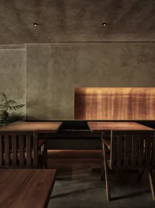 A modern restaurant interior featuring a combination of concrete and wooden elements with warm lighting.