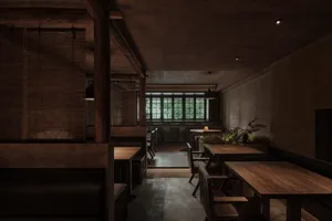 Interior of a restaurant featuring wooden tables, concrete flooring, and metallic accents.