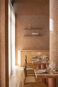 Restaurant interior featuring wooden tables, stone walls, and industrial-style decor.
