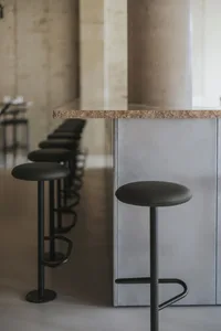 A minimalist modern cafe interior with a concrete countertop and stools.
