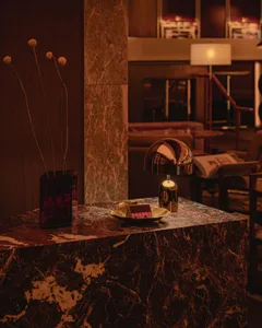 A modern living room with a marble table featuring a spherical lamp and a vase with dried flowers.
