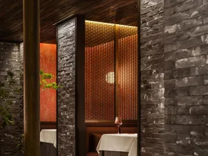 A cozy restaurant setting with brick walls, featuring a booth with a tablecloth and wine glass.