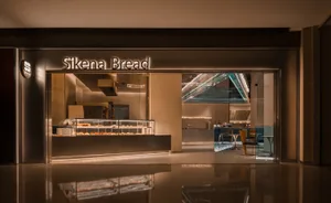 A bakery storefront with warm, modern lighting displaying baked goods inside a glass case.