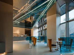 Modern coffee shop interior with glass walls and concrete flooring.