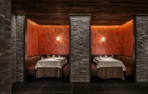 Industrial-themed restaurant with brick and concrete boundary walls, featuring table settings and ambient lighting.