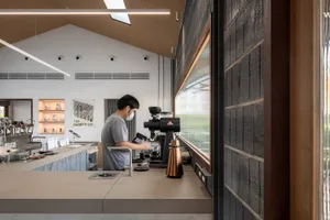 A coffee shop featuring a concrete counter with a barista preparing coffee.