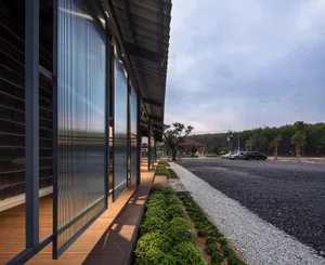 Modern building with metallic panels and wooden walkway.