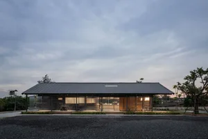 A minimalist outdoor café with a metal roof, tables, and chairs under the open sky.