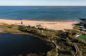 Aerial view of a beach resort with sandy shores, water, and greenery.