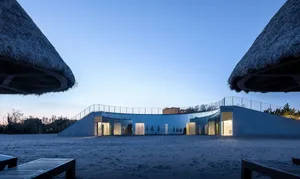 A modern architectural building with glass walls against a clear blue sky.