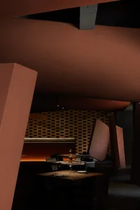 Modern industrial styled restaurant interior with concrete walls, leather chairs, and wood tables.
