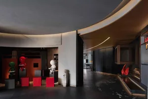 Modern lobby with concrete walls, black tiles, and red stools.