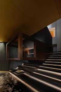 Modern minimalist staircase with metallic steps and handrail, illuminated from below.