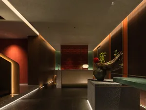 A modern interior design of a hotel front desk reception area featuring concrete and wood materials.