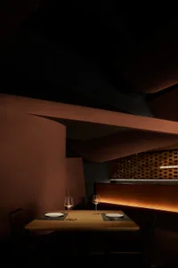 Modern restaurant interior with dark wooden walls, glass elements, and ambient lighting
