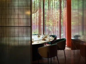 A modern restaurant interior featuring a round table, chairs, and wine glasses.