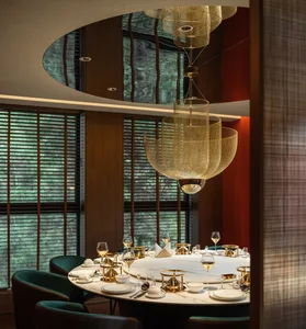 A modern restaurant interior with a round table, brass accents, and marble finishes.