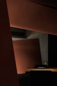 Interior view of a modern restaurant with minimalist concrete wall and wooden flooring.