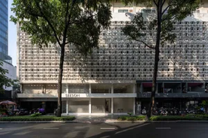 A concrete facade of an office building, featuring a repetitive geometric pattern and large windows.